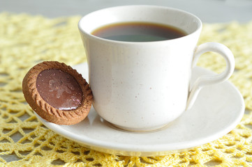 A tea cup with a round biscuit 