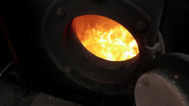 man shoveling coal into steam engine oven. old locomotive technology.