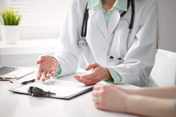 Fototapeta premium Close up of doctor and patient sitting at the desk near the window in hospital