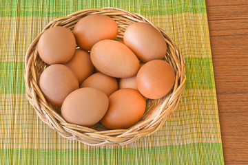 Raw organic brown eggs in wicker basket put on bamboo mat