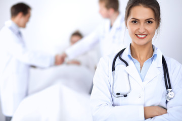 Fototapeta premium Female doctor smiling on the background with patient in the bed