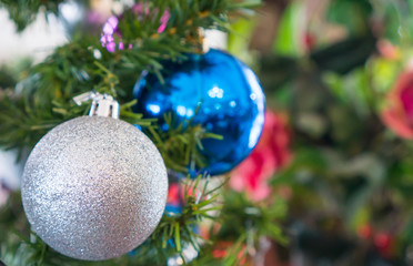 Christmas ball in silver and blue color with glitter texture hanging on the artificial Christmas tree for decoration, Decoration for Christmas tree