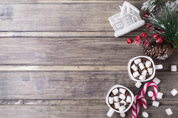 Christmas still life - two cups of hot chocolate with marshmallow, candies, toy house and branch of fir with berries. Copy space