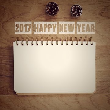 2017 happy new year words and blank note book paper on wood