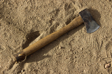 Rustic hatchet/axe lying in dirt on ground with shoe prints