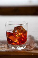 Whiskey with ice on a winter background