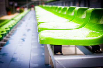 Close up chair green,.green plastic stadium seats arranged in a row. The image has been made before the beginning of a tennis game,.Blurred background of crowd of people at the stadium