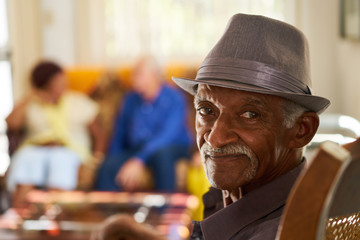 Senior Black Man With Hat Looking At Camera In Hospice - Powered by Adobe