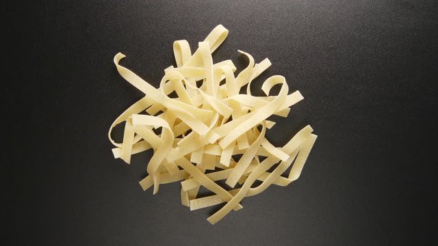 TOP VIEW: Fettuccine pastas fill on a black table (stop motion)