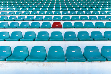 Obraz premium Single red seat or bench in the middle or center of green chair in the stadium.