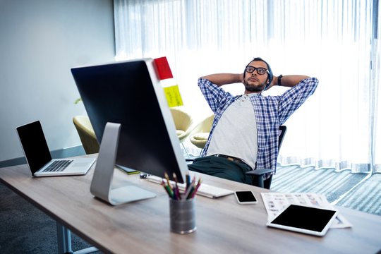 Casual man with hands behind hand resting at desk