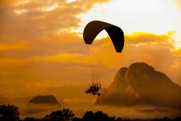 Silhouette paraglider on sunset sky background