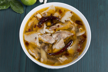 Chicken Tom Yum on the wooden table in green, thai food