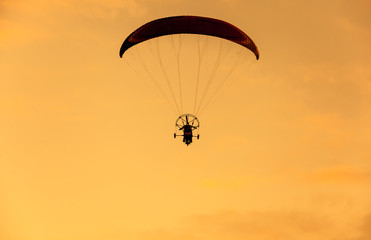 Silhouette of para moter  flies on background of sunset sky