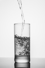pouring water on glass on white background