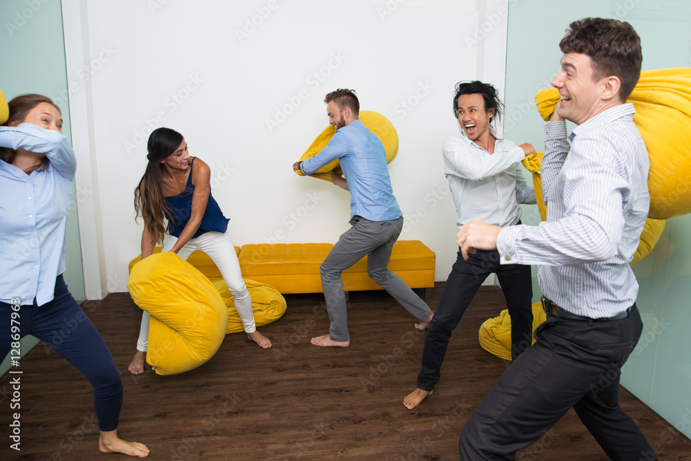 Wall mural ecstatic multiethnic friends fighting pillows