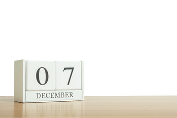 Closeup surface white wooden calendar with black 7 december word on blurred brown wood desk isolated on white background with copy space , selective focus at the calendar