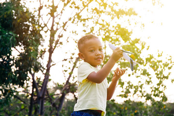 Little kid playing with airplane toy in green park