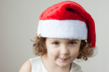 funny little curly blonde girl in a Santa hat
