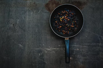 Poster The failure on kitchen: burnt charred vegetables in frying pan on dark shabby background © yolya_ilyasova