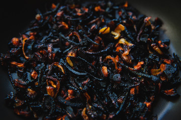 The failure on kitchen: burnt charred vegetables in frying pan on dark shabby background