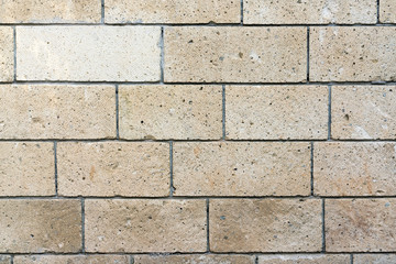 Beige wall lined with stone tile, background, texture