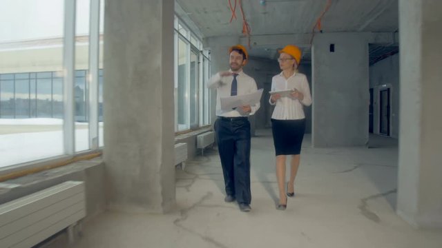 Architect and investor, businesspeople checking new building inder construction. Smooth camera movement, steadycam shot. 4K.