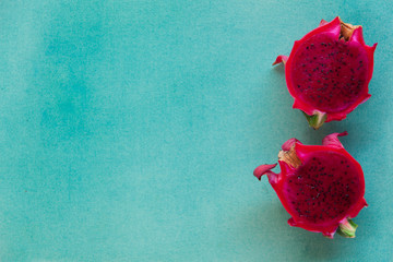 Colorful minimalistic still life of two halves red dragon fruit on a bright blue textured background.