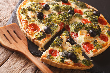 Delicious tart with chicken, broccoli, tomatoes and olives close-up. Horizontal