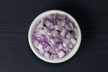 red onion slices in a bowl on a wooden background