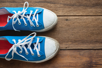 Blue shoes on a wooden background with copy space.