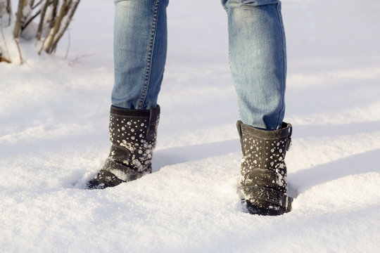 Woman's legs with blue jeans and black shoes in a snow