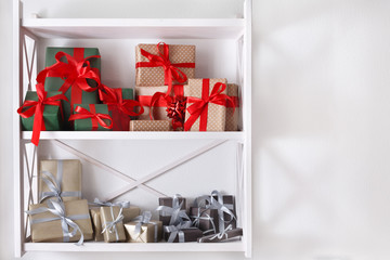 Holiday presents, gift boxes on white shelves at wall background