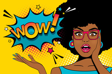 Wow pop art  face. Sexy surprised young african woman with open mouth and afro hairstyle in glasses and Wow speech bubble. Vector colorful background in pop art retro comic style. © irina_levitskaya