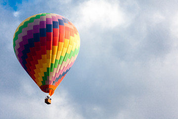 Beautiful peaceful background - hot air balloon rises very high in blue sky above white clouds, bright sun shines