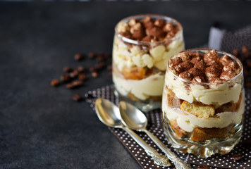 Classic tiramisu in a glass jar on black background