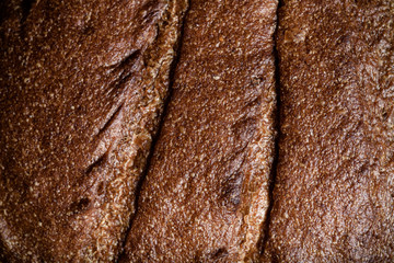 Closeup view on texture of crust of fresh rye bread. Toned