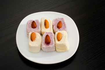 Top view of purple and white Turkish Delight with almonds, black background