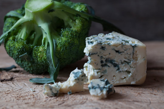 Slices of Danish Blue cheese and broccoli on an wooden table, se