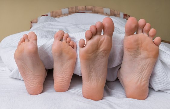 Feet of young couple in bed.