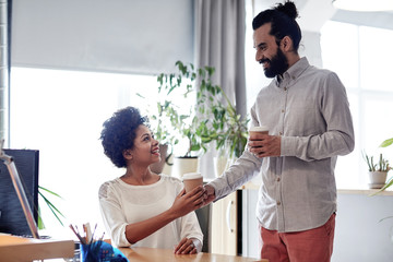 happy man bringing coffee to woman in office