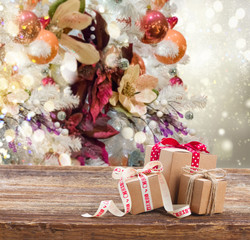 three handmade gift boxes on wooden table, christmas decorated tree in background