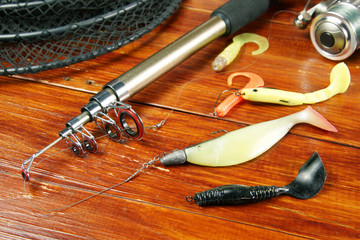 Fishing still life with various silicone baits and spinning on wooden background