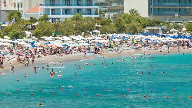 Rhodes Greece People Vacationing at the Popular Eli Beach Swimming in Blue Mediterranean Water and Sunbathing with Umbrellas on a Sunny Summer Day
