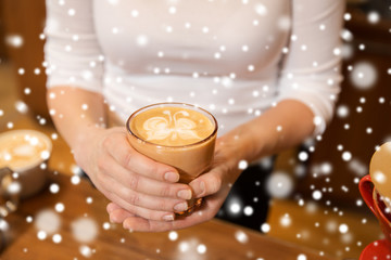 close up of hands with latte art in coffee cup