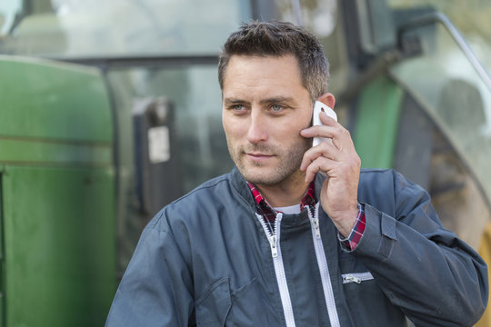 Farmer Leaning On The Tractor Using A Phone