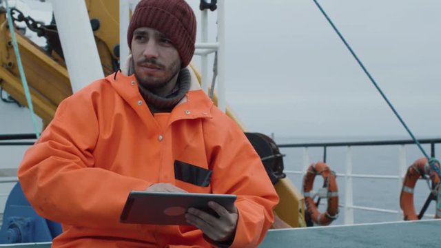 Casualy Dressed Fisherman Using Tablet Computer with Navigation Maps while Traveling on Ship. Shot on RED Cinema Camera in 4K (UHD). 