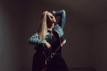 Pretty blonde woman with longboard in dark room