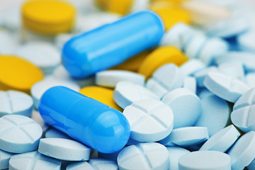 two light blue pills on a pile of medical pills