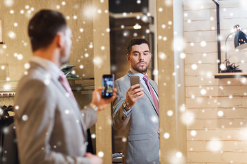 man in suit taking mirror selfie at clothing store